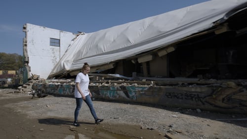Image of Colleen Daly walking in front of a building impacted by Hurricane Helene.