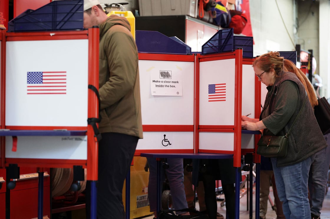 Voters stand behind partitions as they mark their ballots.