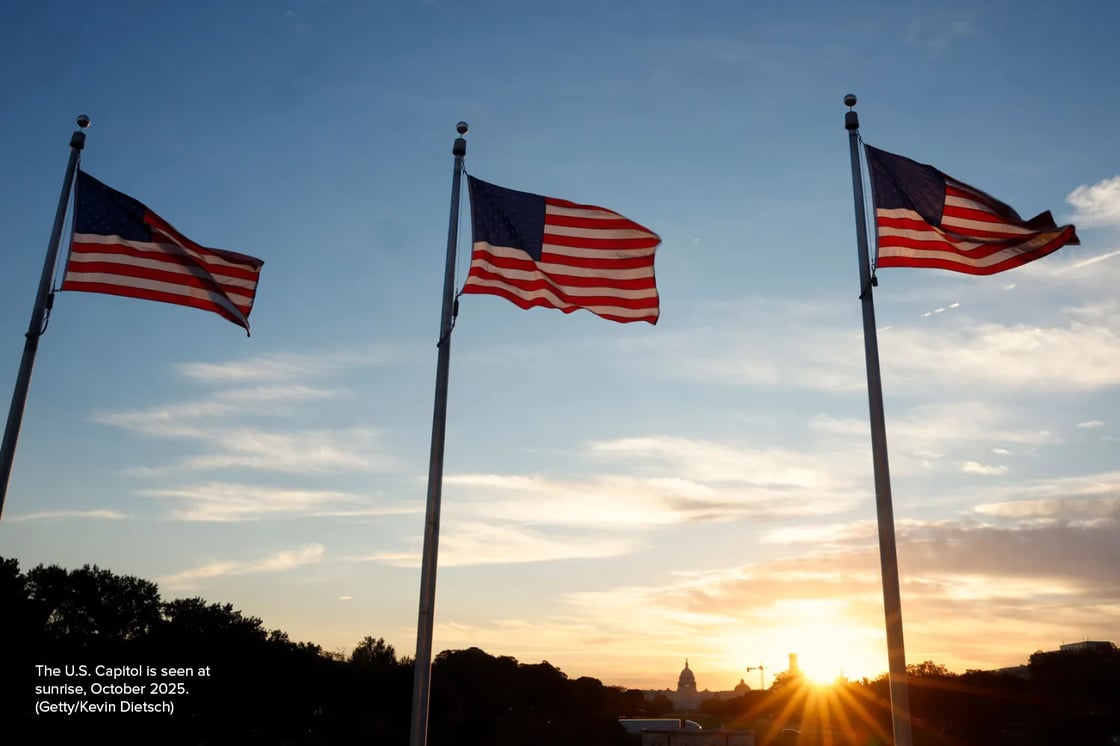 Three American flags and the US Capitol are seen at sunset.